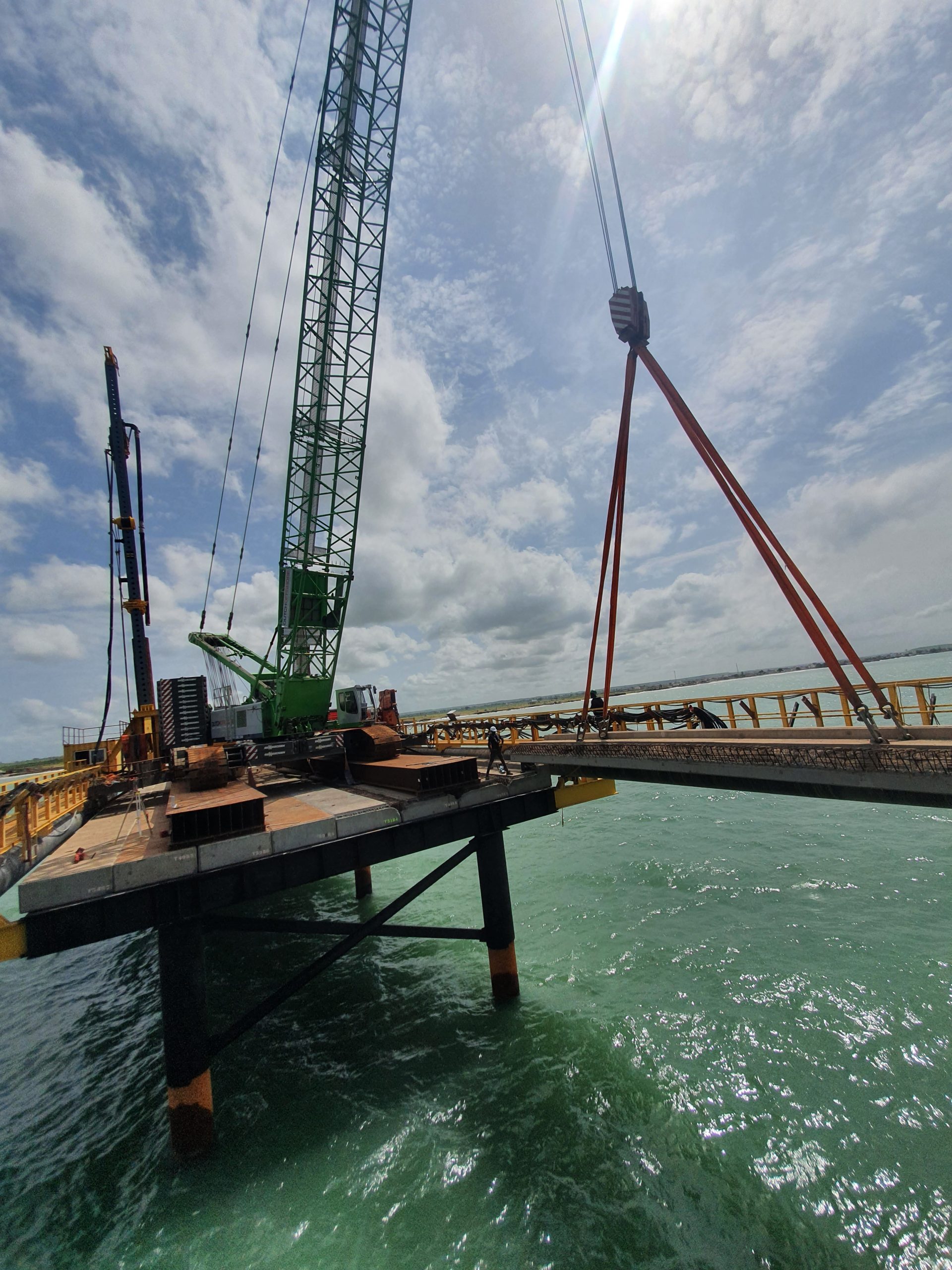Deux grues construisent une structure moderne sous un ciel nuageux.